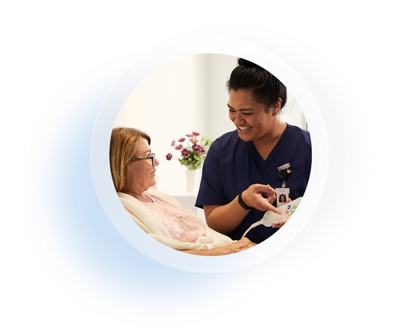 carer smiling to elderly patient with responder nurse ca;; handset in hand
