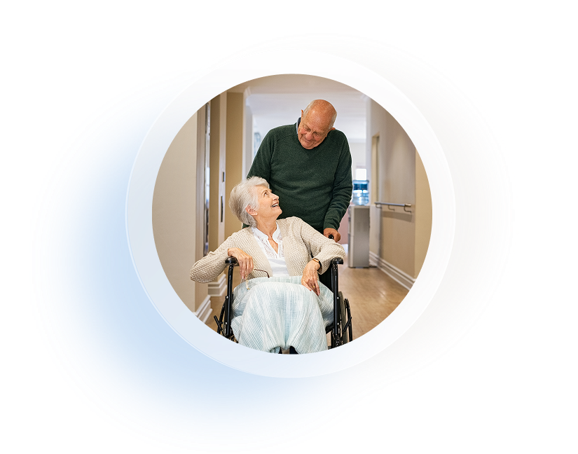 Elderly man pushing elderly women in wheelchair