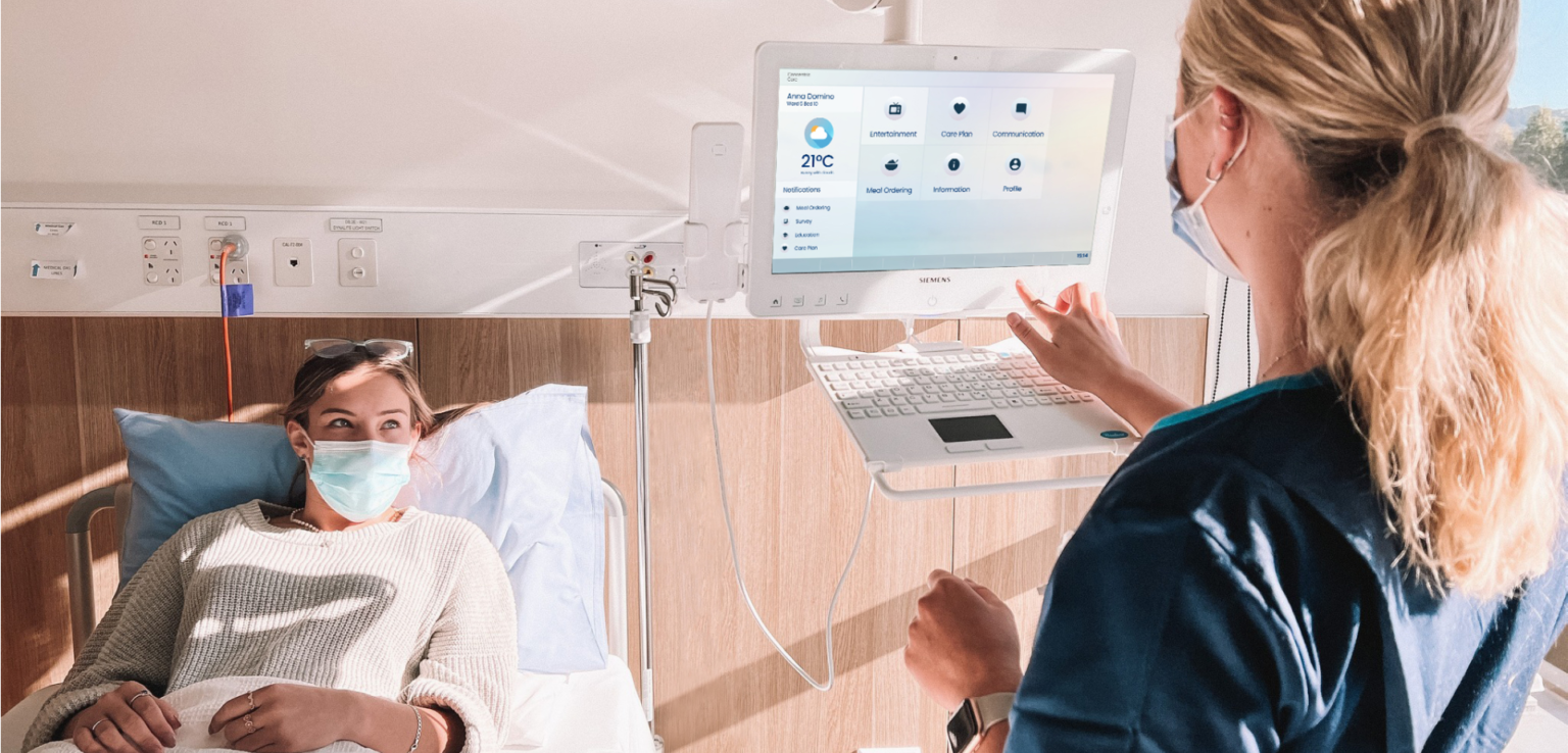 Elderly patient with daughter and nurse talking around HiMed Cockpit with My Care Plan screen copy 1 (2)