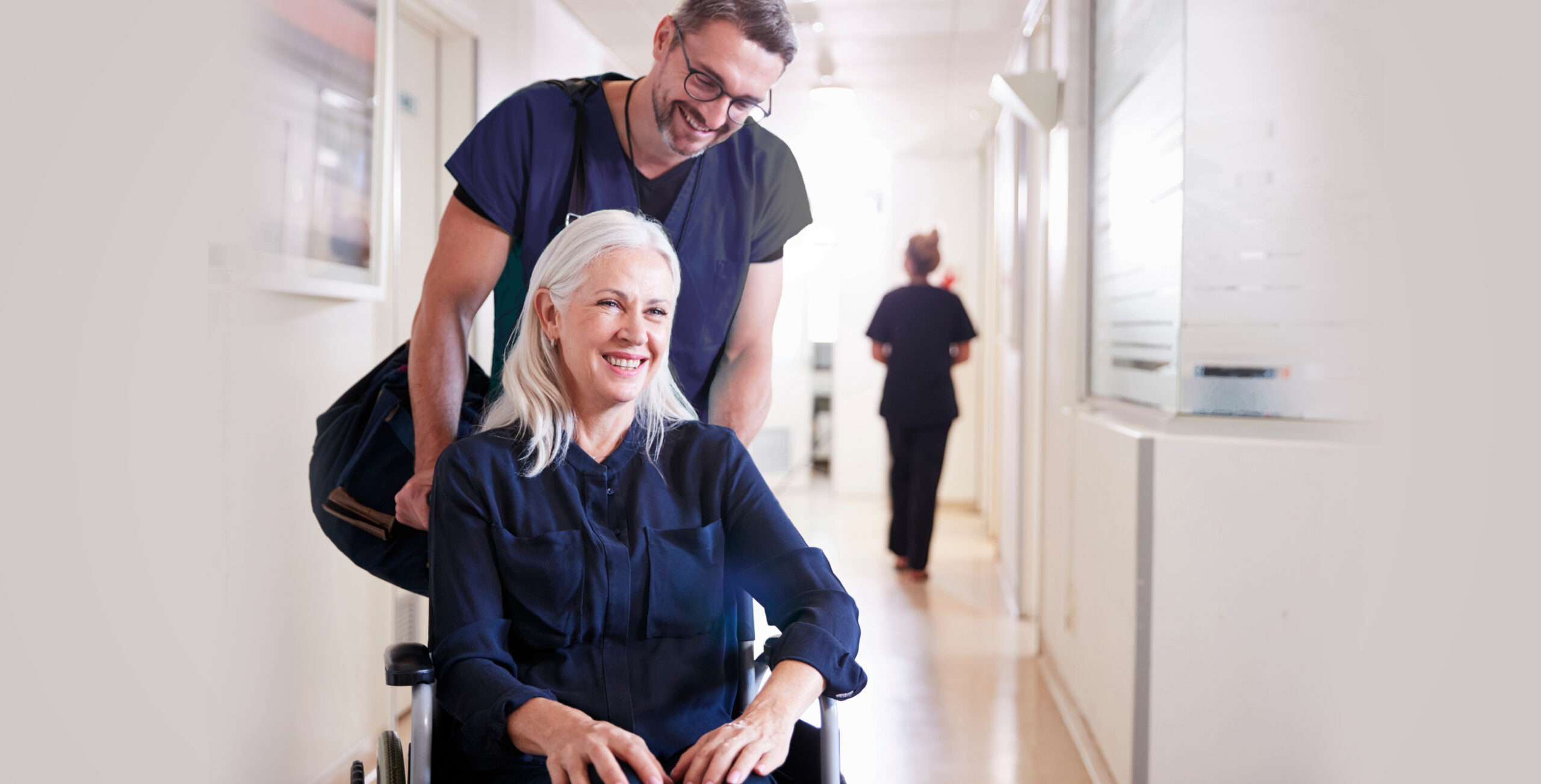 Nurse pushing elderly patient in wheelchair